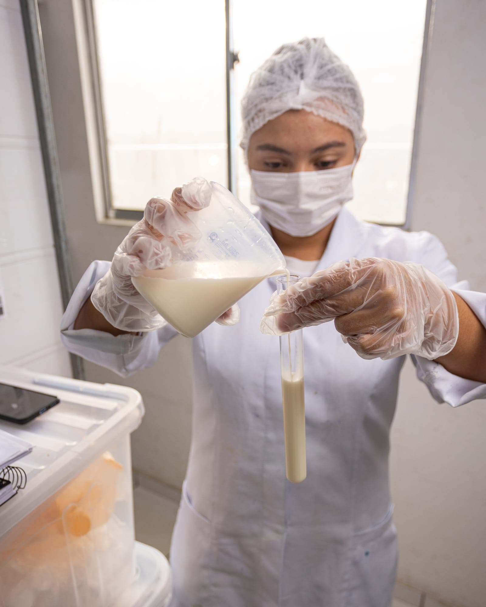 Analista do laboratório testando uma amostra de leite na proveta